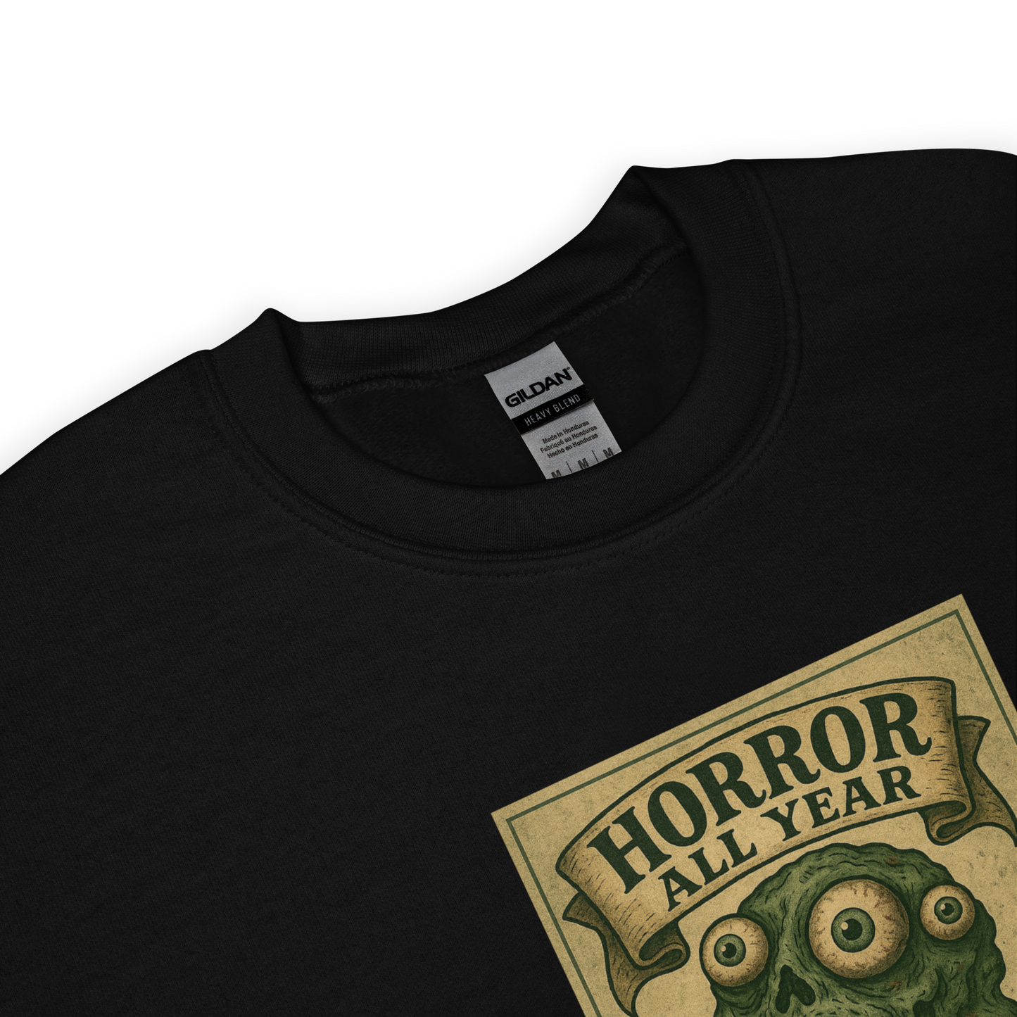 This is a zoom in of a black sweatshirt that is a vintage-style illustration of a zombie-themed ice cream cone with a green, melting undead face and bulging eyeballs. Above the cone, a horror banner reads "Horror All Year" on a distressed parchment background