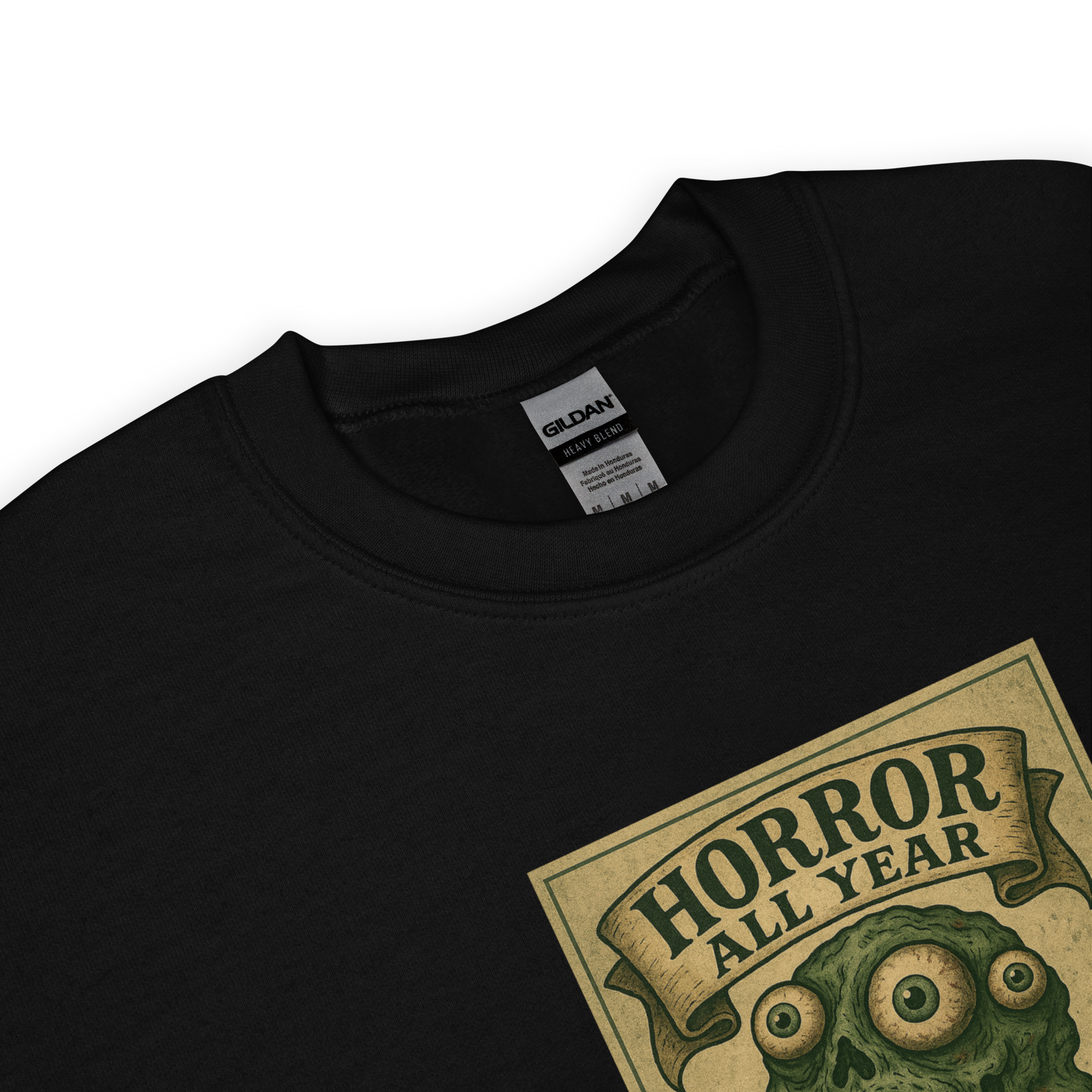 This is a zoom in of a black sweatshirt that is a vintage-style illustration of a zombie-themed ice cream cone with a green, melting undead face and bulging eyeballs. Above the cone, a horror banner reads "Horror All Year" on a distressed parchment background