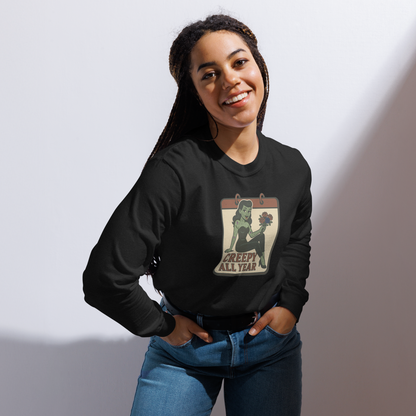 A girl with braids wearing jeans and a black long sleeve t-shirt. The design features a green pinup-style zombie girl holding flowers, with a banner underneath that reads “CREEPY ALL YEAR.”