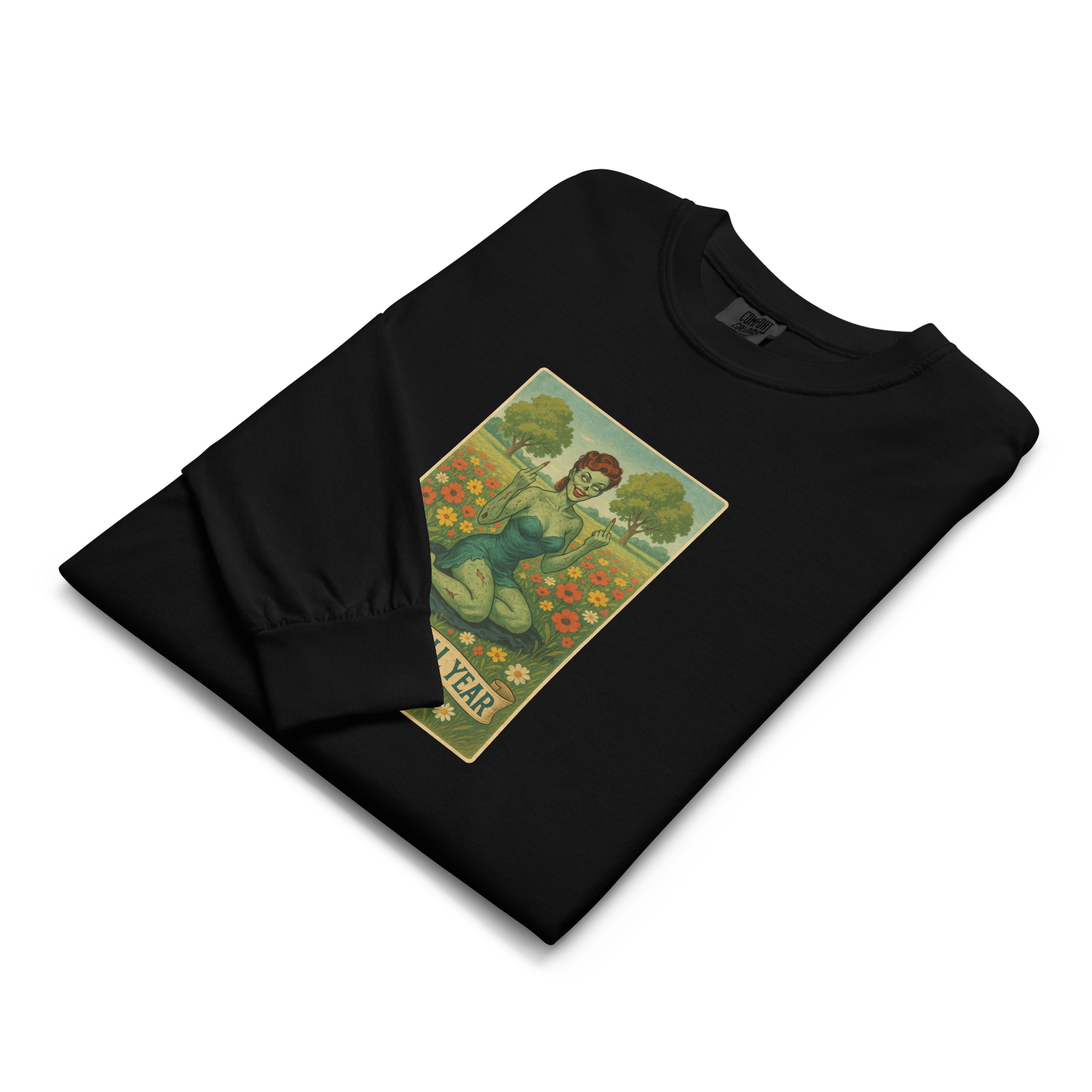 This is a folded black long sleeve shirt with a design illustration of a sassy zombie pinup girl standing in a floral field, wearing tattered lingerie and flipping off the viewer with both hands. She has green skin, vintage curls, and a bold attitude. The design blends horror and humor, with a pastel color palette and creepy cute vibes