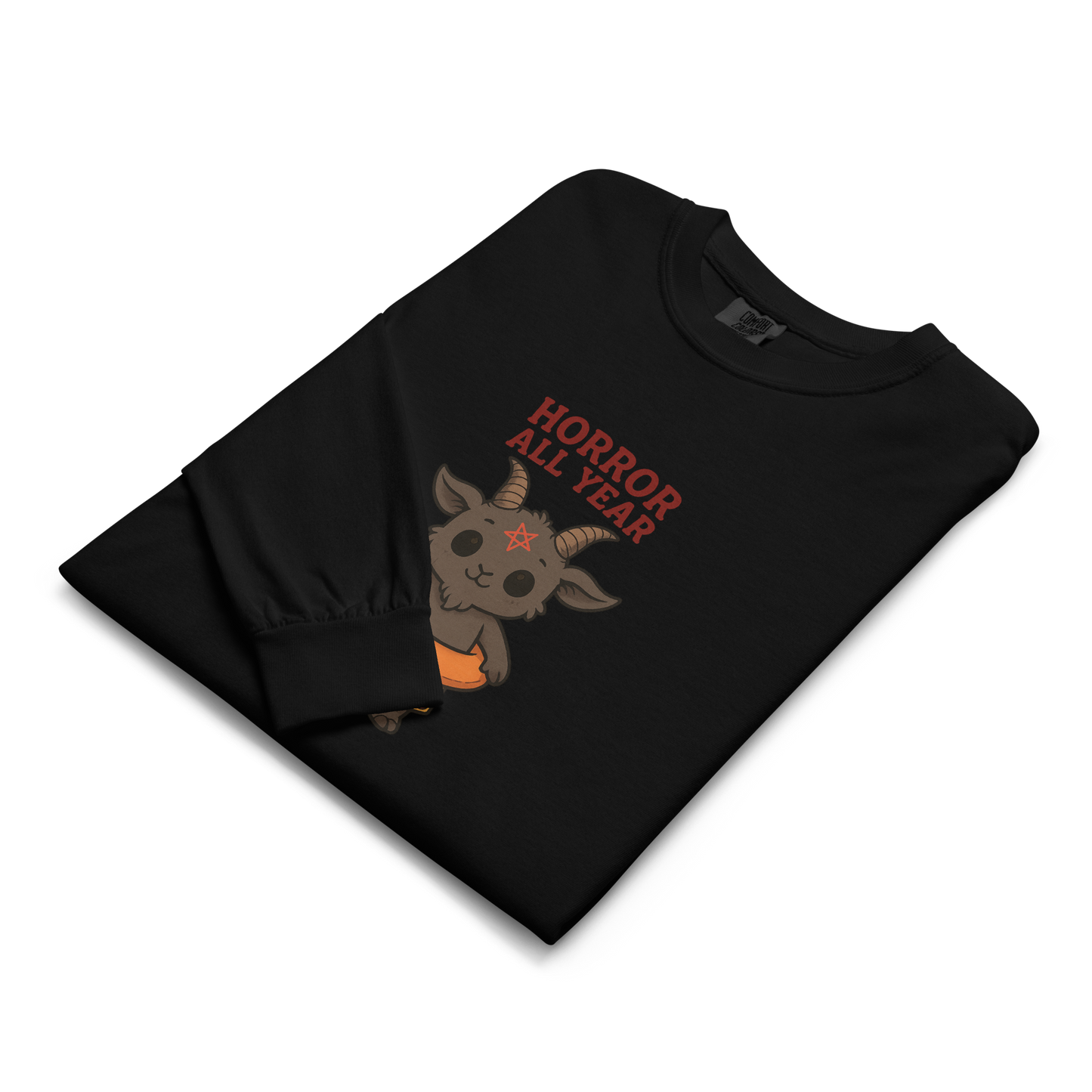 This is a folded zoom in of a black long sleeve shirt with a cartoon illustration of a baby Baphomet goat with curved horns and a playful grin, wearing bright floral swim trunks while floating in a colorful inner tube. The character is set against a light background with the bold text “Horror All Year” above in red letters
