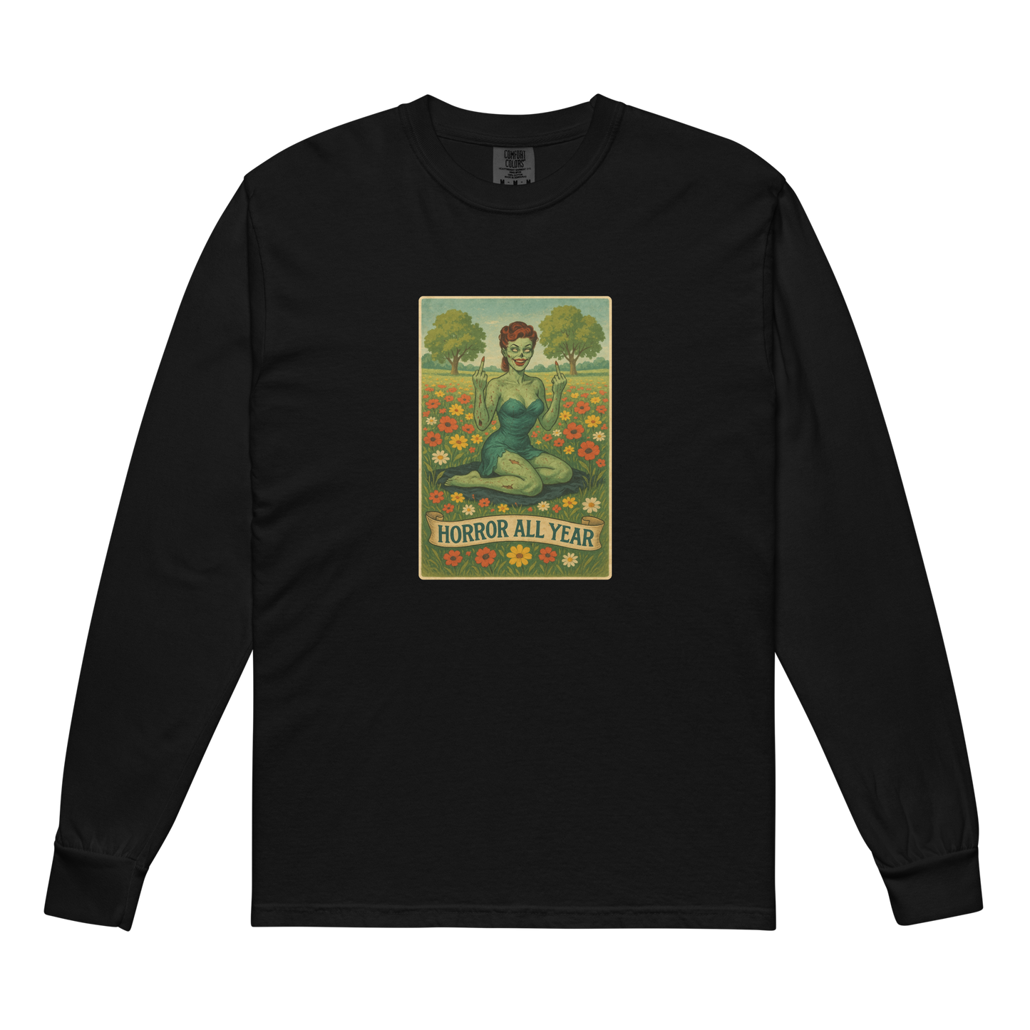 This is a black long sleeve shirt with a design illustration of a sassy zombie pinup girl standing in a floral field, wearing tattered lingerie and flipping off the viewer with both hands. She has green skin, vintage curls, and a bold attitude. The design blends horror and humor, with a pastel color palette and creepy cute vibes