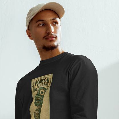 This is a man with a baseball hat wearing a black long sleeve shirt that is a vintage-style illustration of a zombie-themed ice cream cone with a green, melting undead face and bulging eyeballs. Above the cone, a horror banner reads "Horror All Year" on a distressed parchment background