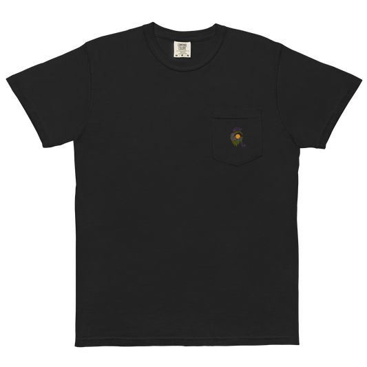 This is a black pocket t-shirt with a design of a hand-drawn wreath made of moss-covered branches wraps around a glowing sun. The wreath is decorated with purple and blue flowers, small amethyst and fluorite crystals, and strands of hanging moss. The words “Witchy” curve above the wreath and “All Year” sits on the bottom right 