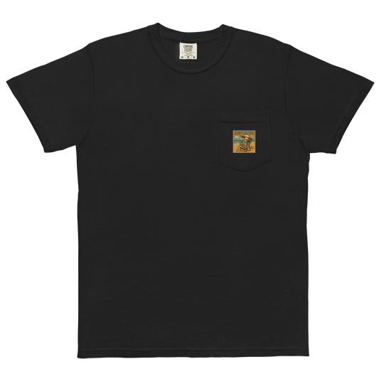 This is a black pocket t-shirt with a retro-style illustration of a grinning skeleton lounging on a beach chair under an orange umbrella. The skeleton is holding a pumpkin-shaped drink cup with a straw and relaxing by the ocean, with a bright sun in the sky and a life preserver in the sand. The words “Creepy All Year” appear boldly at the top