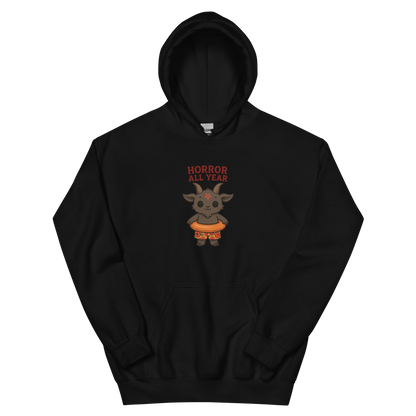 This is a black hoodie with a cartoon illustration of a baby Baphomet goat with curved horns and a playful grin, wearing bright floral swim trunks while floating in a colorful inner tube. The character is set against a light background with the bold text “Horror All Year” above in red letters