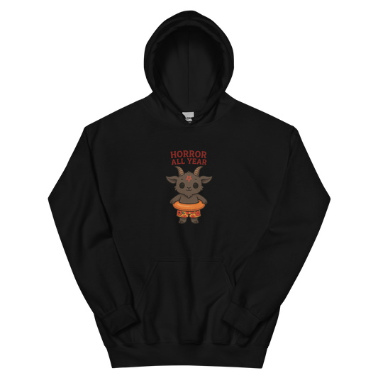 This is a black hoodie with a cartoon illustration of a baby Baphomet goat with curved horns and a playful grin, wearing bright floral swim trunks while floating in a colorful inner tube. The character is set against a light background with the bold text “Horror All Year” above in red letters
