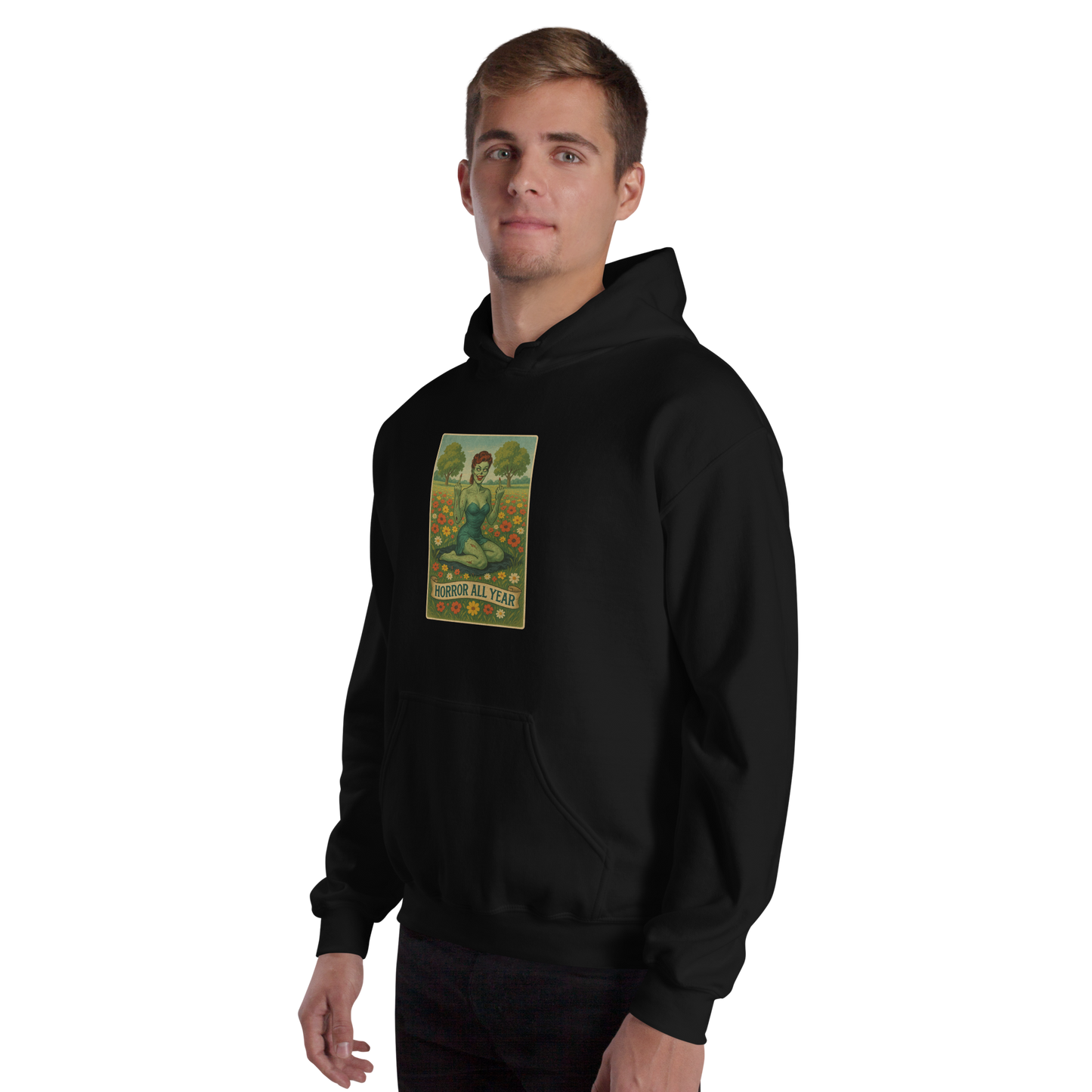 This is a man with blonde hair wearing a black hoodie with a design illustration of a sassy zombie pinup girl standing in a floral field, wearing tattered lingerie and flipping off the viewer with both hands. She has green skin, vintage curls, and a bold attitude. The design blends horror and humor, with a pastel color palette and creepy cute vibes.