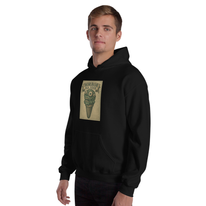 This is a man with light hair wearing a black hoodie that is a vintage-style illustration of a zombie-themed ice cream cone with a green, melting undead face and bulging eyeballs. Above the cone, a horror banner reads "Horror All Year" on a distressed parchment background