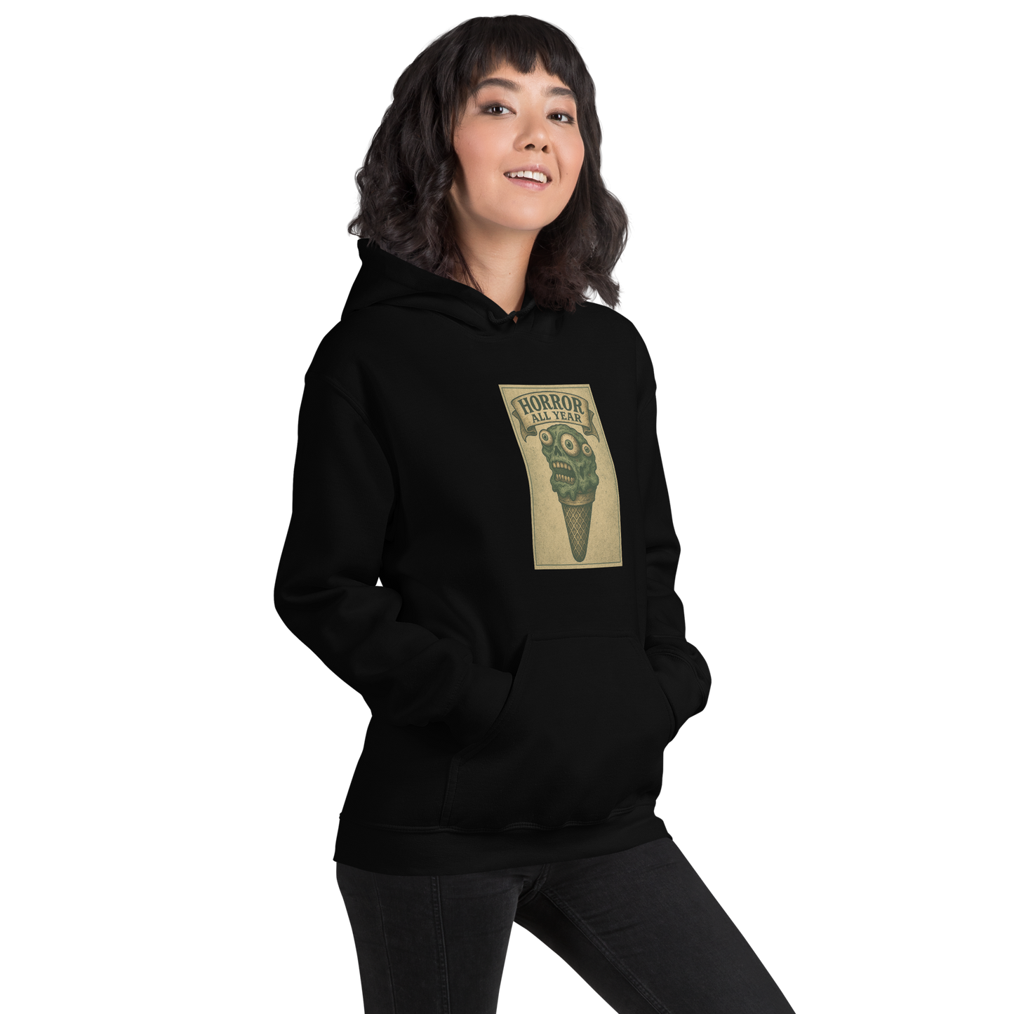 This is a woman with dark hair wearing a black hoodie that is a vintage-style illustration of a zombie-themed ice cream cone with a green, melting undead face and bulging eyeballs. Above the cone, a horror banner reads "Horror All Year" on a distressed parchment background
