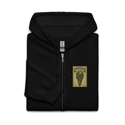 This is a folded black zip-up hoodie that is a vintage-style illustration of a zombie-themed ice cream cone with a green, melting undead face and bulging eyeballs. Above the cone, a horror banner reads "Horror All Year" on a distressed parchment background