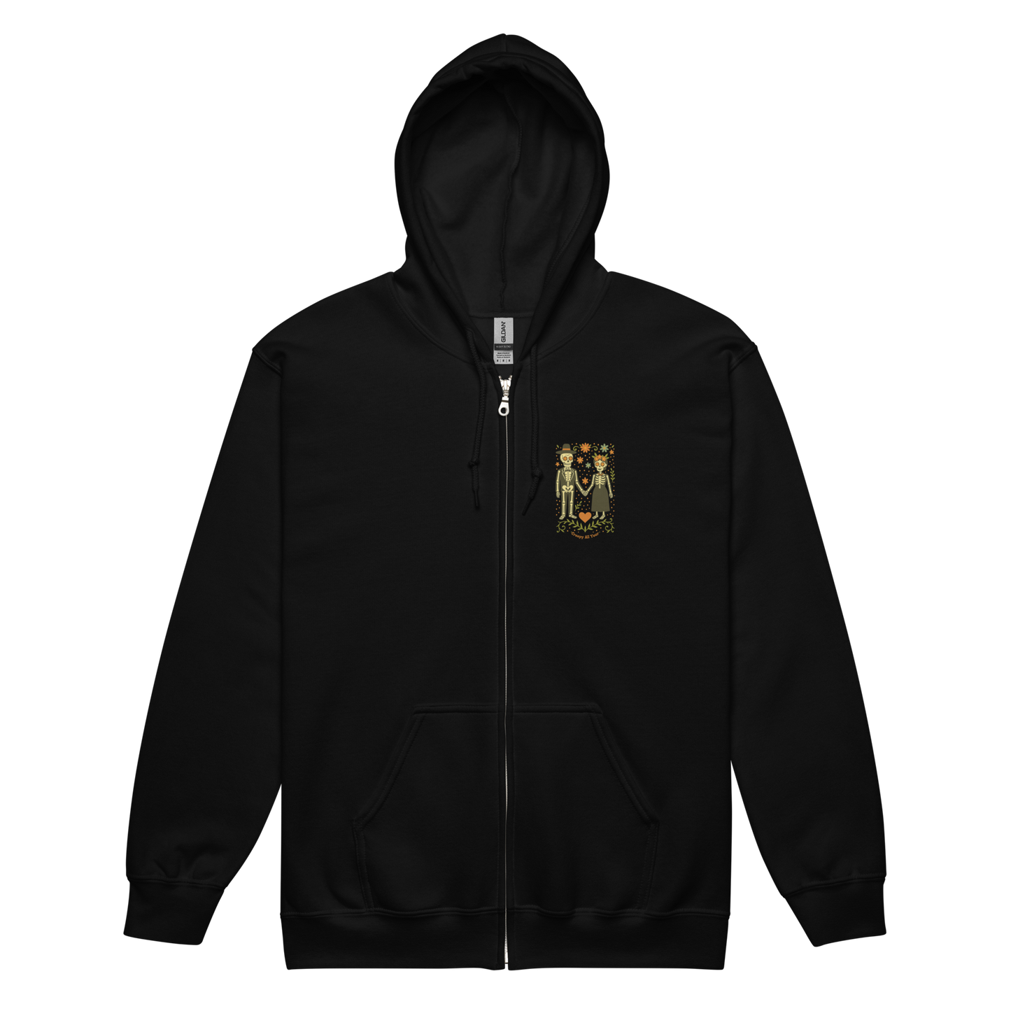 This is a black zip up hoodie with a Día de los Muertos–style illustration of a male and female skeleton holding hands, surrounded by marigolds, vines, and folk art patterns. The skeletons wear traditional black clothing, the man in a suit and hat, the woman with a floral crown with a red heart and leaves at the bottom and the text Creepy All Year. Rendered in warm tones of orange, green, and cream, symbolizing eternal love and remembrance