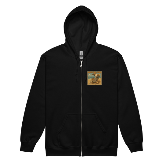 This is a black zip-up hoodie with a retro-style illustration of a grinning skeleton lounging on a beach chair under an orange umbrella. The skeleton is holding a pumpkin-shaped drink cup with a straw and relaxing by the ocean, with a bright sun in the sky and a life preserver in the sand. The words “Creepy All Year” appear boldly at the top