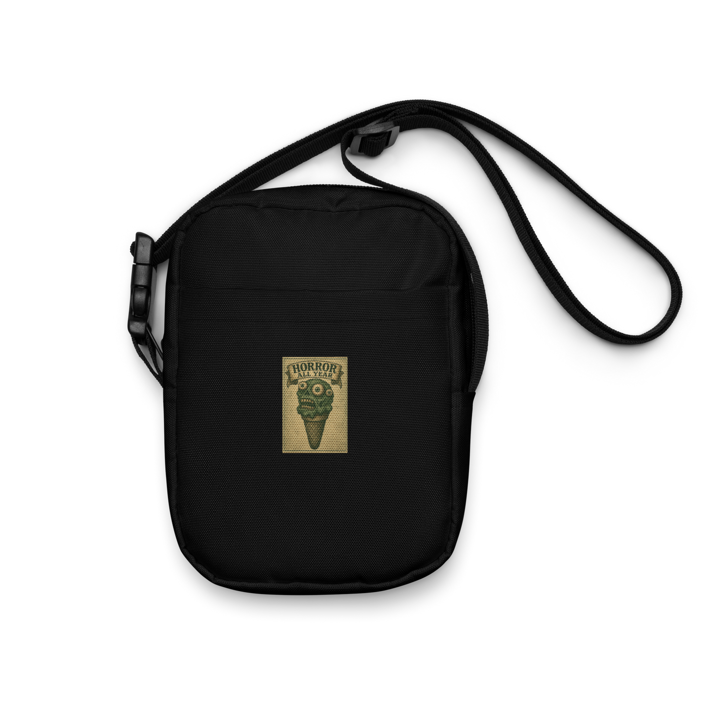 This is a black crossbody bag that is a vintage-style illustration of a zombie-themed ice cream cone with a green, melting undead face and bulging eyeballs. Above the cone, a horror banner reads "Horror All Year" on a distressed parchment background