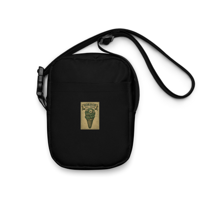 This is a black crossbody bag that is a vintage-style illustration of a zombie-themed ice cream cone with a green, melting undead face and bulging eyeballs. Above the cone, a horror banner reads "Horror All Year" on a distressed parchment background
