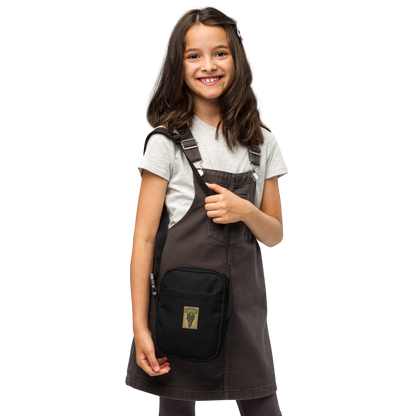 This is a girl with dark hair wearing a black crossbody bag that is a vintage-style illustration of a zombie-themed ice cream cone with a green, melting undead face and bulging eyeballs. Above the cone, a horror banner reads "Horror All Year" on a distressed parchment background