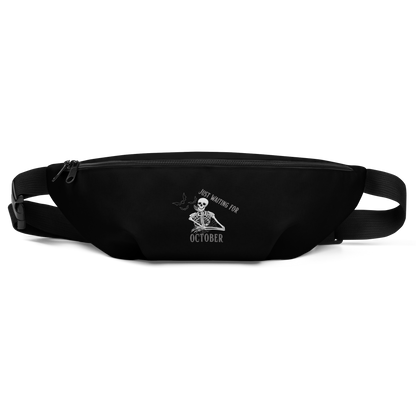This is a black waist bag fanny pack that has a bored skeleton with his head resting in his hand and he has spider webs and bats around him and the text reads just waiting for October
