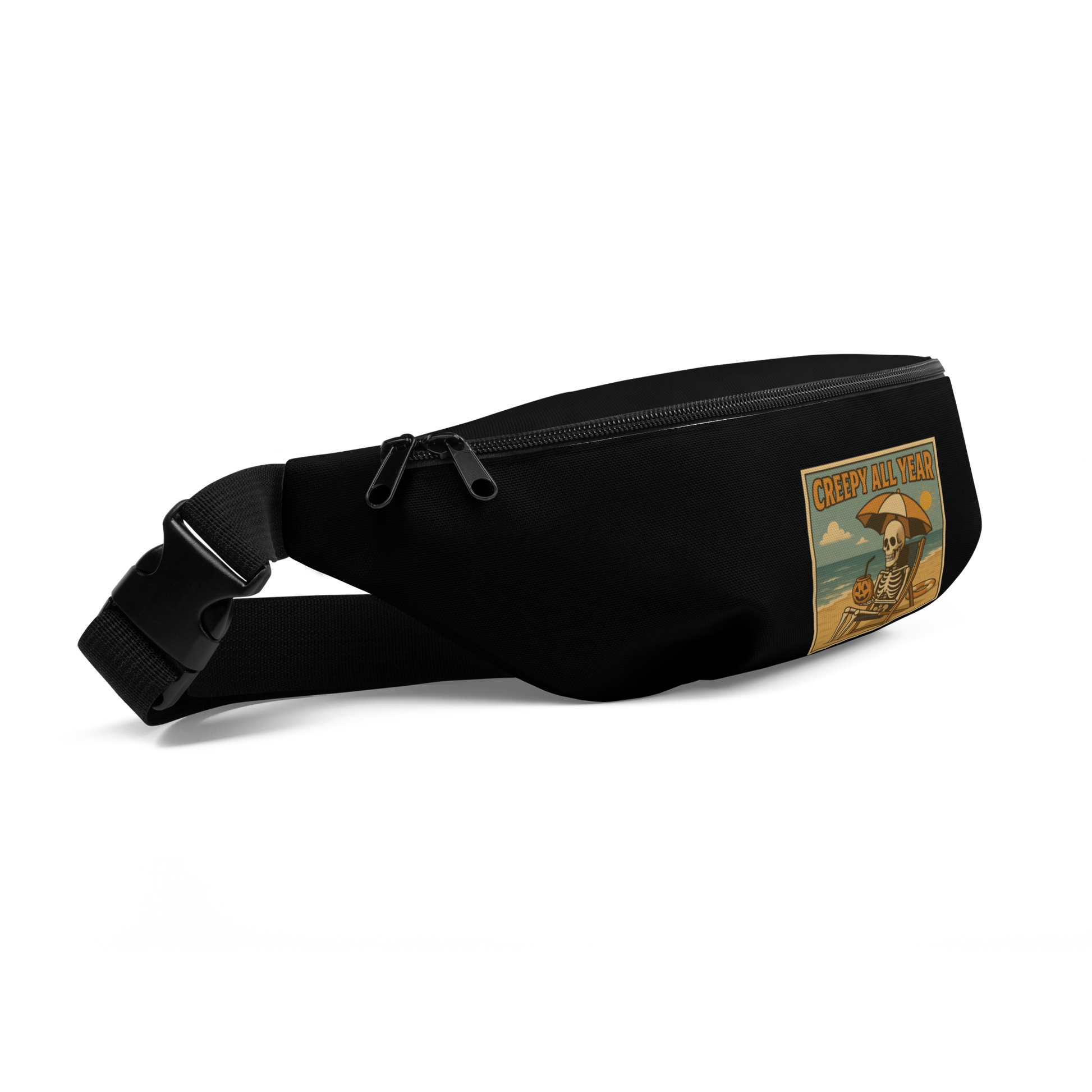 This is a black waist bag fanny pack with a retro-style illustration of a grinning skeleton lounging on a beach chair under an orange umbrella. The skeleton is holding a pumpkin-shaped drink cup with a straw and relaxing by the ocean, with a bright sun in the sky and a life preserver in the sand. The words “Creepy All Year” appear boldly at the top 