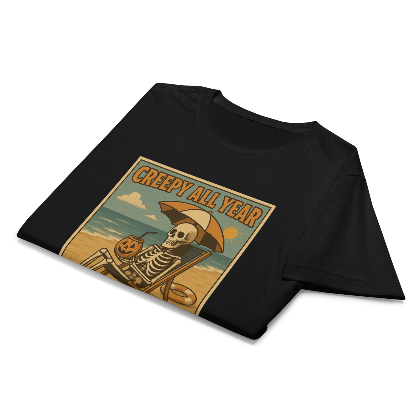 This is a folded, black style woman's t-shirt with a retro-style illustration of a grinning skeleton lounging on a beach chair under an orange umbrella. The skeleton is holding a pumpkin-shaped drink cup with a straw and relaxing by the ocean, with a bright sun in the sky and a life preserver in the sand. The words “Creepy All Year” appear boldly at the top
