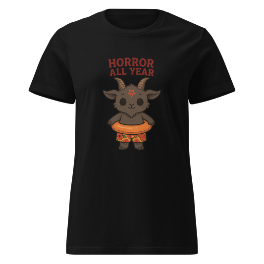 This is a women's black t-shirt with a cartoon illustration of a baby Baphomet goat with curved horns and a playful grin, wearing bright floral swim trunks while floating in a colorful inner tube. The character is set against a light background with the bold text “Horror All Year” above in red letters