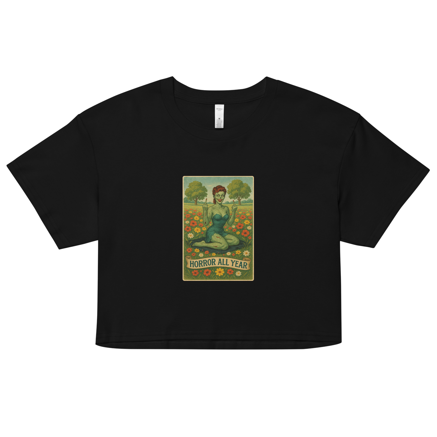 This is a black crop top with a design illustration of a sassy zombie pinup girl standing in a floral field, wearing tattered lingerie and flipping off the viewer with both hands. She has green skin, vintage curls, and a bold attitude. The design blends horror and humor, with a pastel color palette and creepy cute vibes