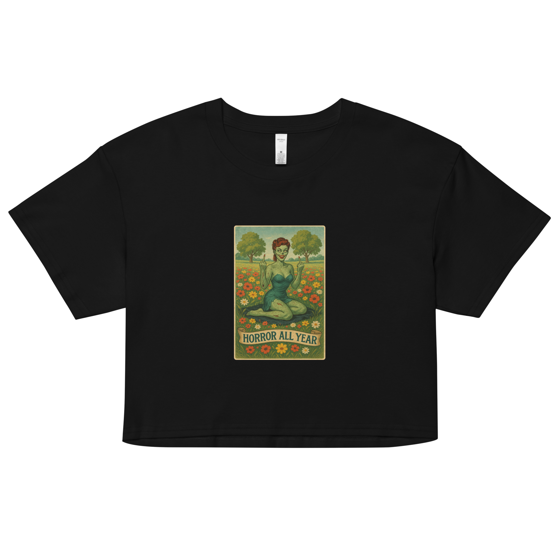 This is a black crop top with a design illustration of a sassy zombie pinup girl standing in a floral field, wearing tattered lingerie and flipping off the viewer with both hands. She has green skin, vintage curls, and a bold attitude. The design blends horror and humor, with a pastel color palette and creepy cute vibes