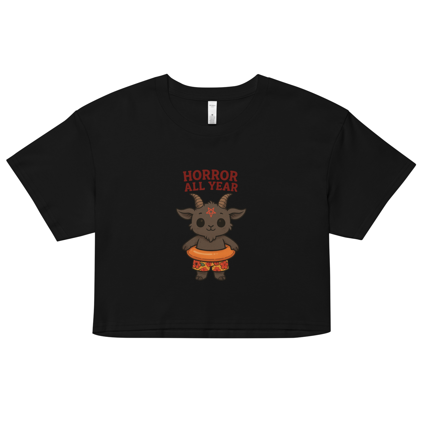 This is a black crop top with a cartoon illustration of a baby Baphomet goat with curved horns and a playful grin, wearing bright floral swim trunks while floating in a colorful inner tube. The character is set against a light background with the bold text “Horror All Year” above in red letters