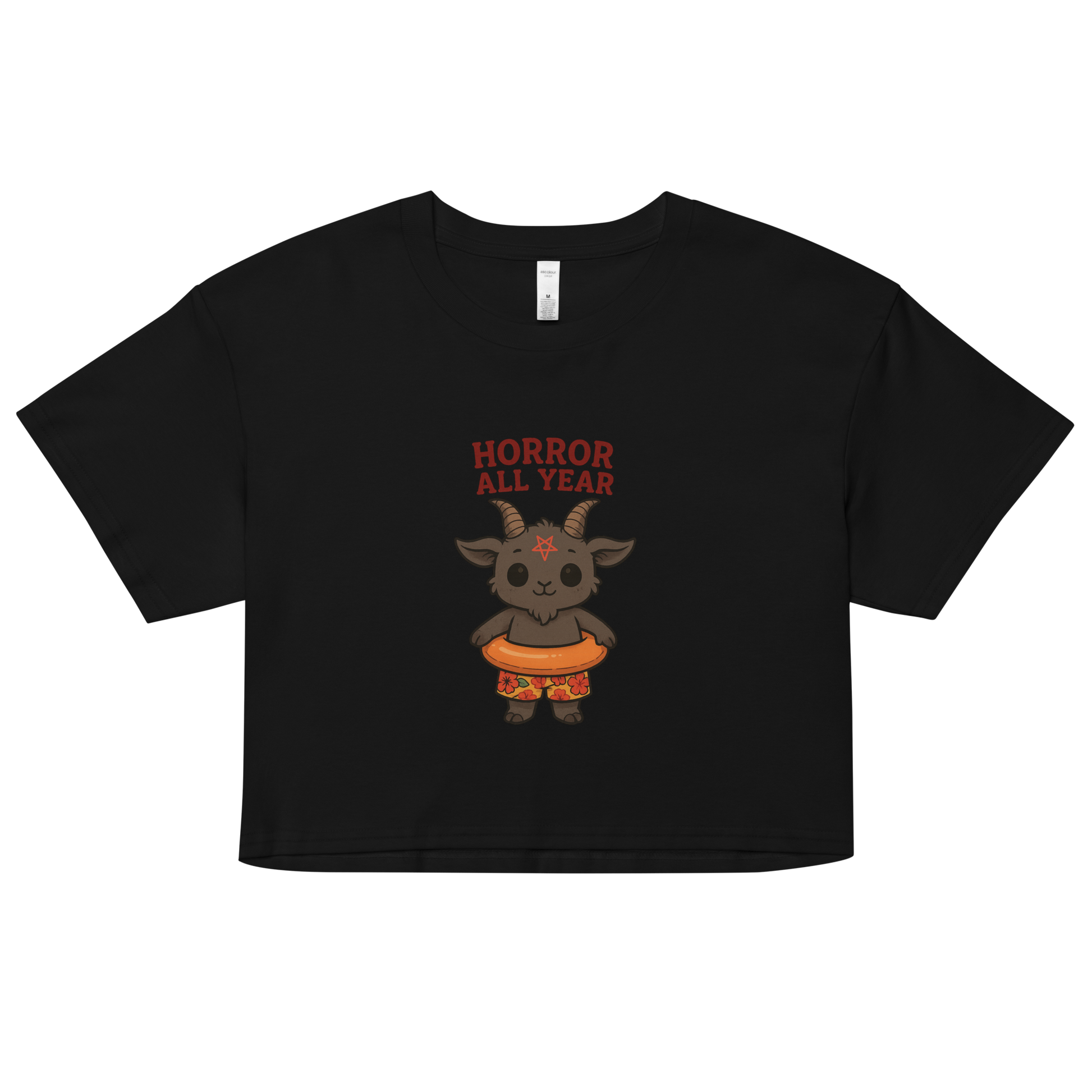 This is a black crop top with a cartoon illustration of a baby Baphomet goat with curved horns and a playful grin, wearing bright floral swim trunks while floating in a colorful inner tube. The character is set against a light background with the bold text “Horror All Year” above in red letters