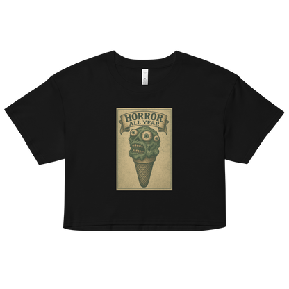 This a black crop top that is a vintage-style illustration of a zombie-themed ice cream cone with a green, melting undead face and bulging eyeballs. Above the cone, a horror banner reads "Horror All Year" on a distressed parchment background