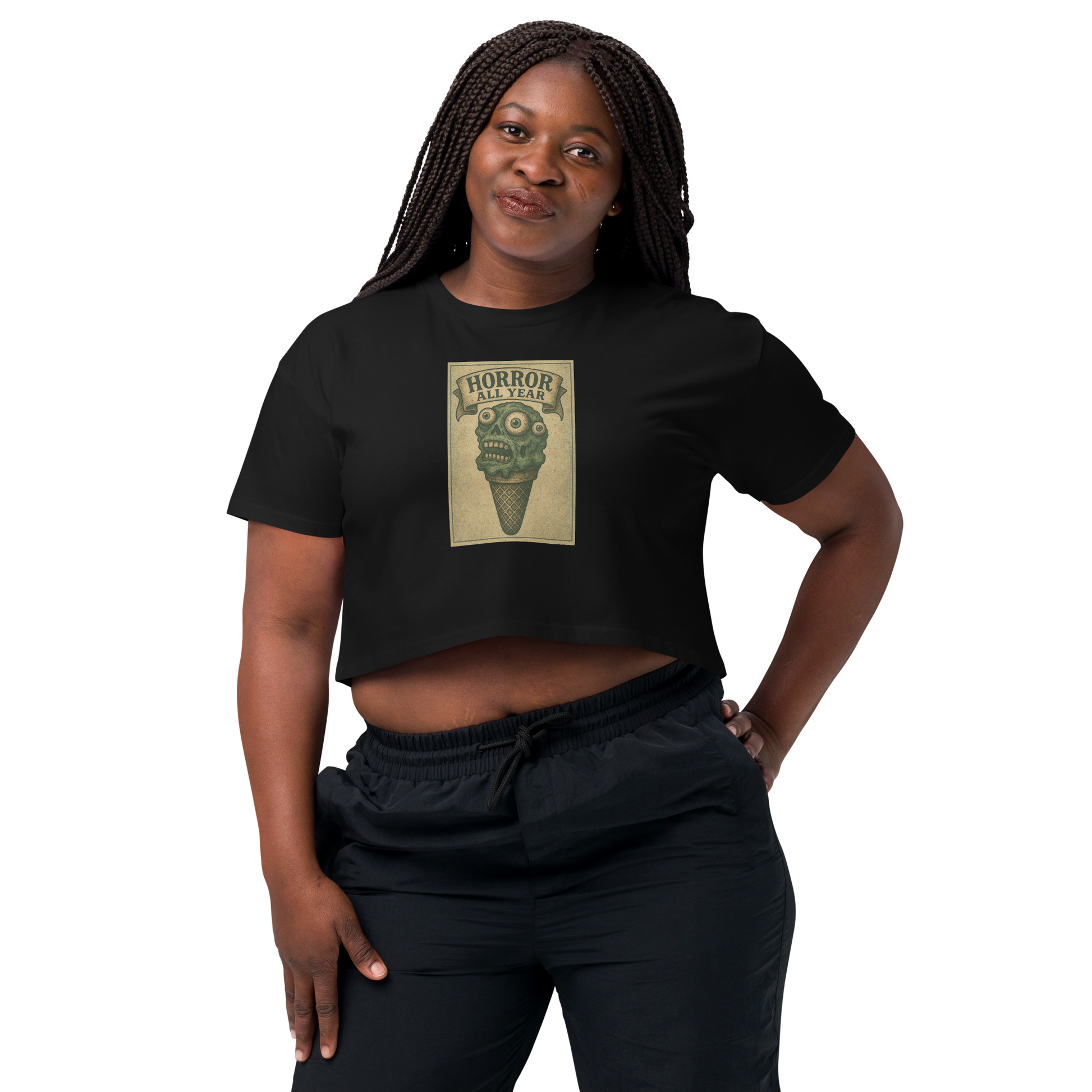 This is a woman with dark braids wearing a black crop top that is a vintage-style illustration of a zombie-themed ice cream cone with a green, melting undead face and bulging eyeballs. Above the cone, a horror banner reads "Horror All Year" on a distressed parchment background