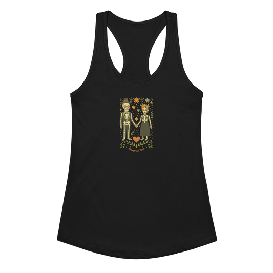 This is a black women's racerback tank top with a Día de los Muertos–style illustration of a male and female skeleton holding hands, surrounded by marigolds, vines, and folk art patterns. The skeletons wear traditional black clothing, the man in a suit and hat, the woman with a floral crown with a red heart and leaves at the bottom and the text Creepy All Year. Rendered in warm tones of orange, green, and cream, symbolizing eternal love and remembrance