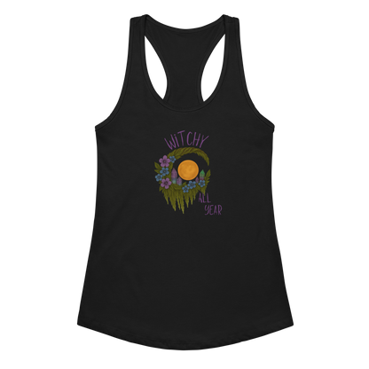 This is a black racerback tank top with a design of a hand-drawn wreath made of moss-covered branches wraps around a glowing sun. The wreath is decorated with purple and blue flowers, small amethyst and fluorite crystals, and strands of hanging moss. The words “Witchy” curve above the wreath and “All Year” sits on the bottom right 

