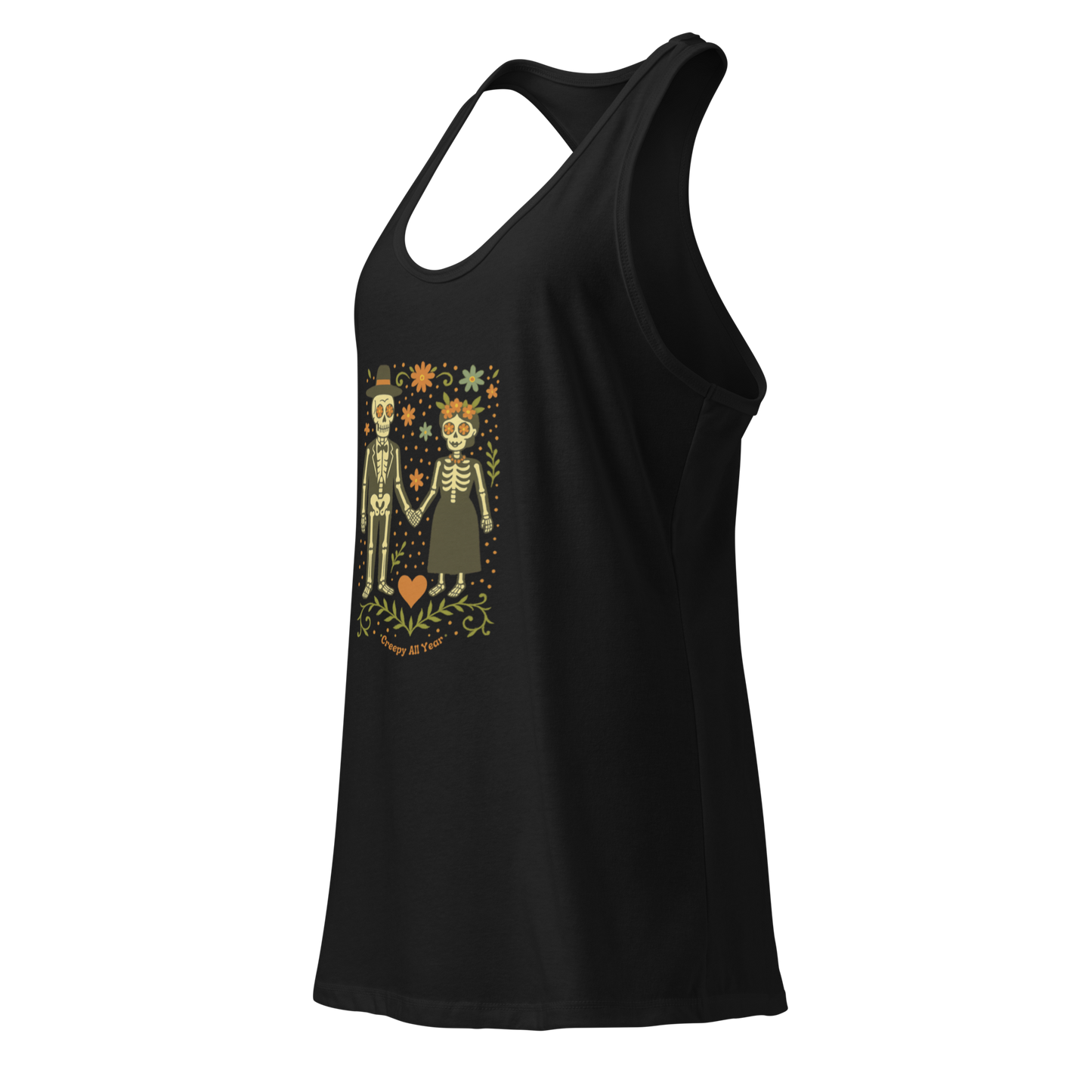 This is a black women's racerback tank top with a Día de los Muertos–style illustration of a male and female skeleton holding hands, surrounded by marigolds, vines, and folk art patterns. The skeletons wear traditional black clothing, the man in a suit and hat, the woman with a floral crown with a red heart and leaves at the bottom and the text Creepy All Year. Rendered in warm tones of orange, green, and cream, symbolizing eternal love and remembrance