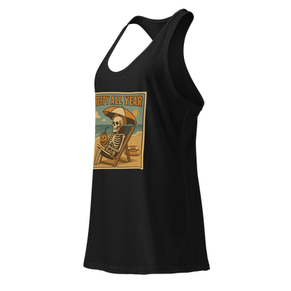 This is a black racerback tank top with a retro-style illustration of a grinning skeleton lounging on a beach chair under an orange umbrella. The skeleton is holding a pumpkin-shaped drink cup with a straw and relaxing by the ocean, with a bright sun in the sky and a life preserver in the sand. The words “Creepy All Year” appear boldly at the top 